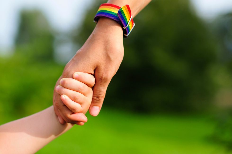 parent with pride rainbow watch holding child's hand