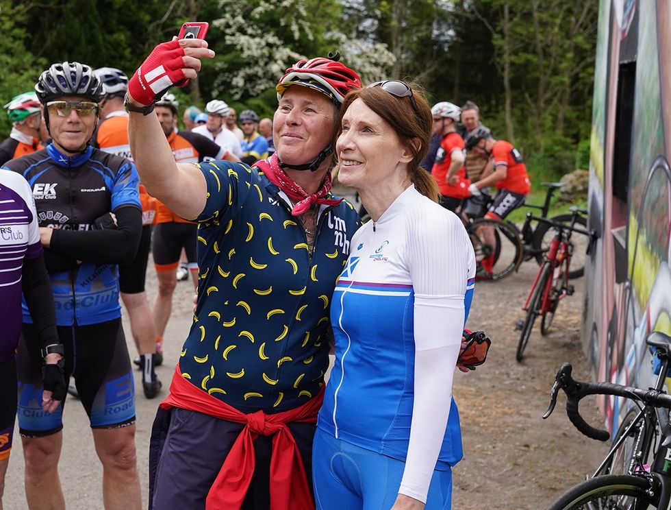 Philippa York in blue and white posing for selfies with fellow cyclists