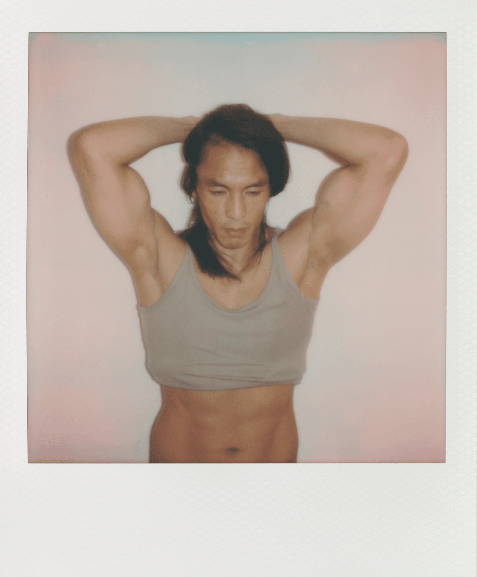 Polaroid portrait of a man posing with his arms raised wearing a sleeveless top.
