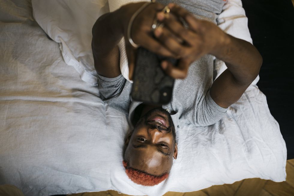 queer person in bed looking at phone