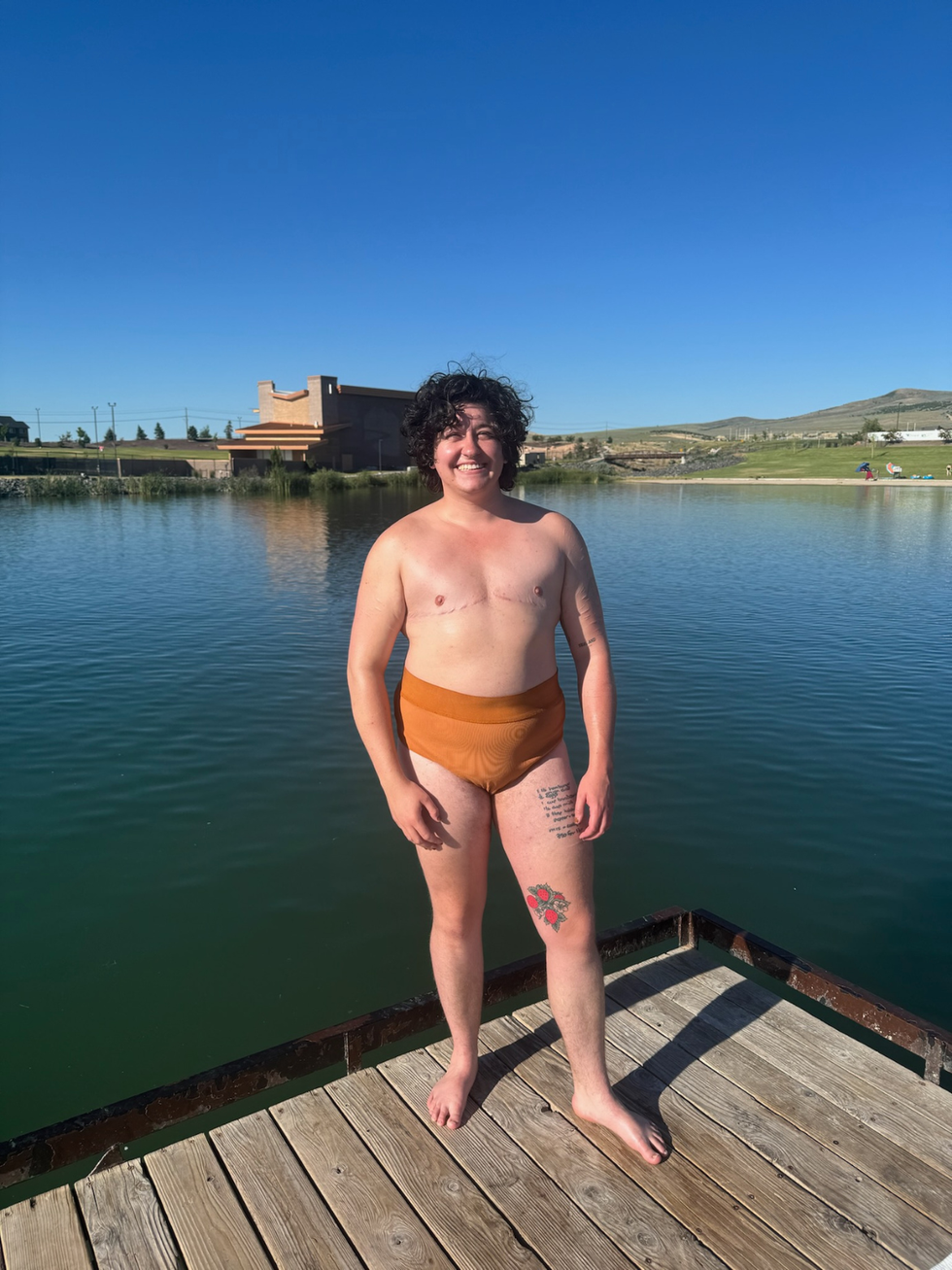 Rowan Smith, the author, a mixed race 25-year-old trans man in the Ruxwood brief 01 in Sienna on a dock on a body of water.