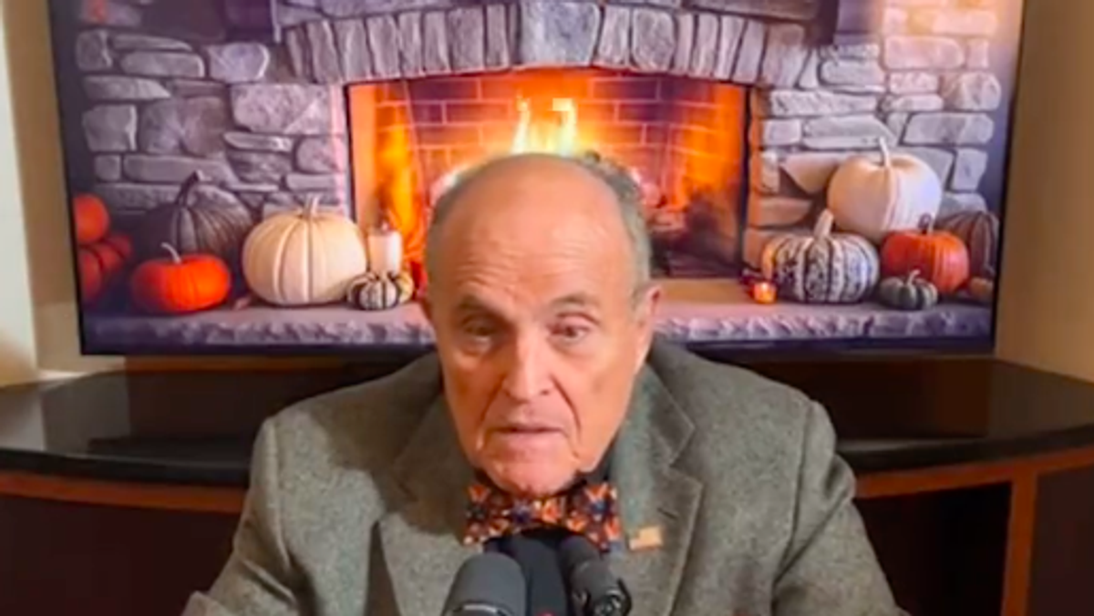 Rudy Giuliani in front of a microphone with a fireplace in the background.