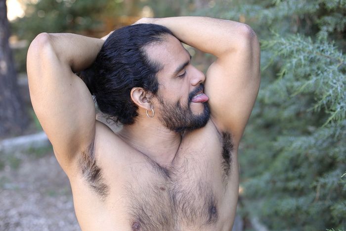 Shirtless ethnic man licking his arms