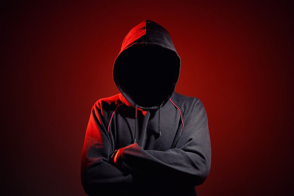 Silhouette af man without face in hood on a red background.