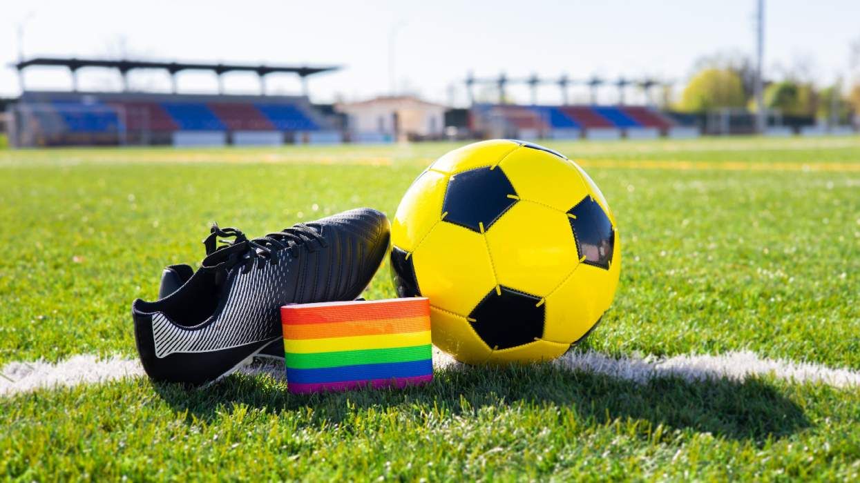 Soccer ball and cleat on field with rainbow armband