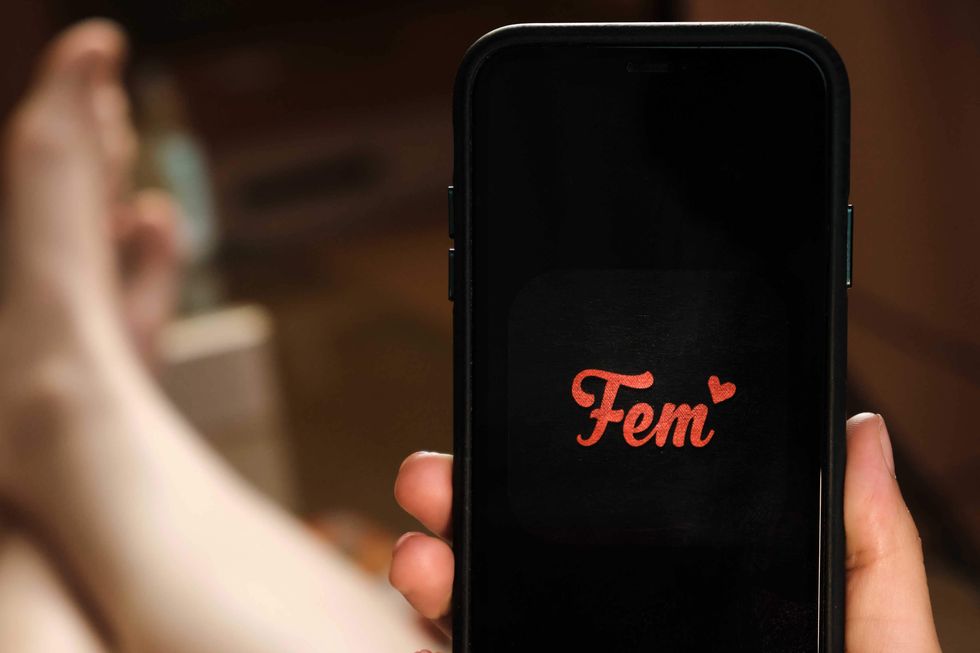 Someone holding a cell phone with the Fem app