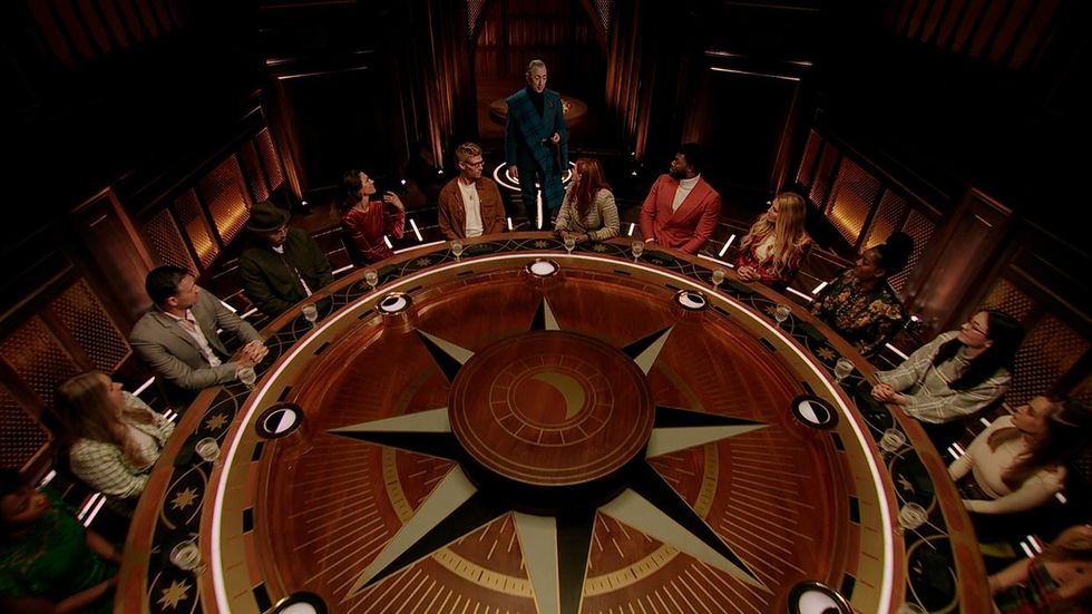 The cast of Traitors deliberate around a round table.