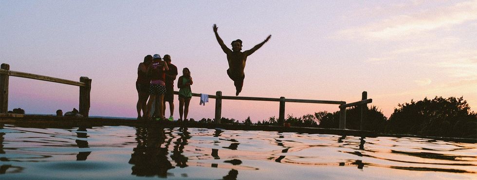 This is a photo of a guy jumping off a dock into a lake.