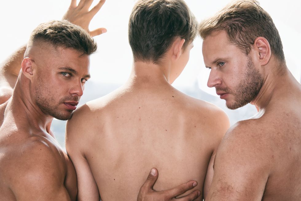 three shirtless men touching each other