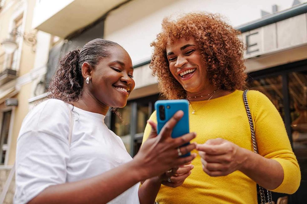 tow people looking at a cell phone and laughing
