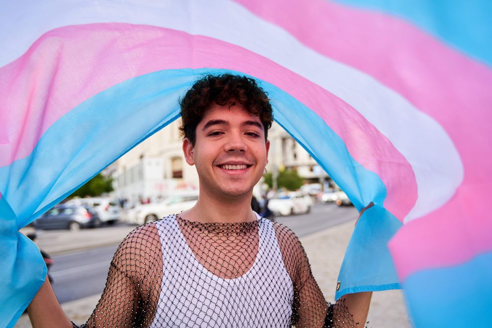 Trans man holding a trans Pride flag.