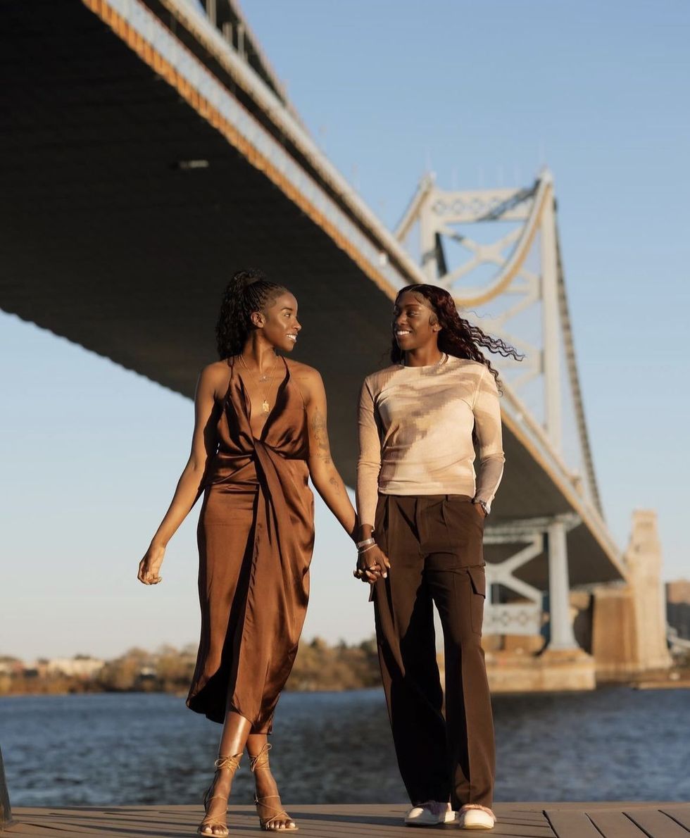 Two Black women hold hands and look lovingly at each other.