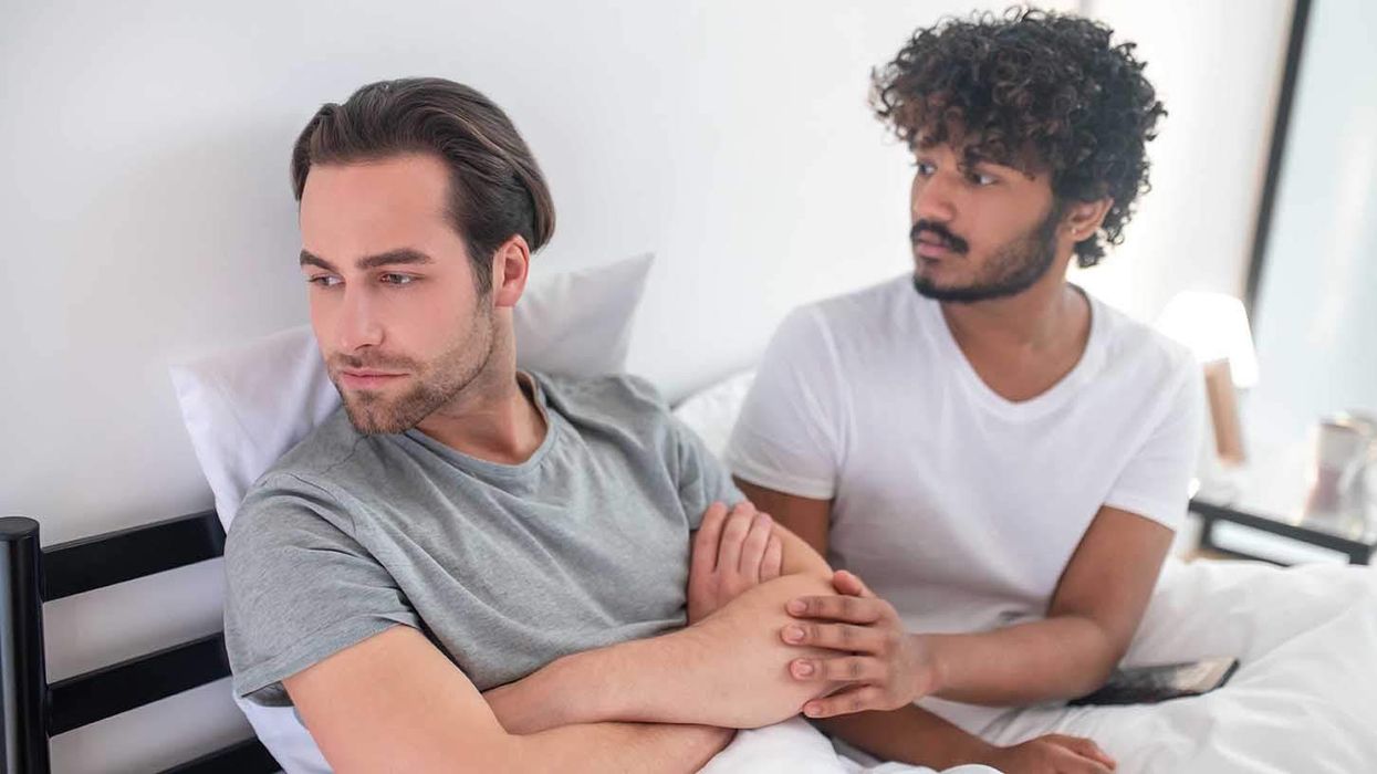 Two gay men angry at each other while sitting in bed