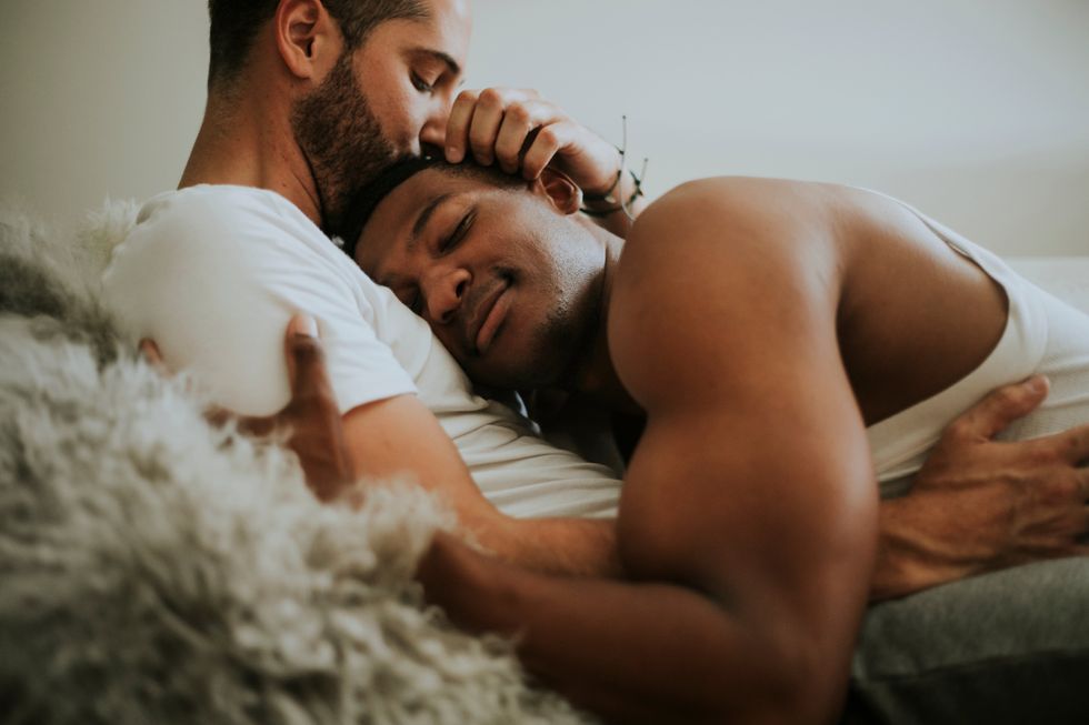 Two gay men cuddling in bed
