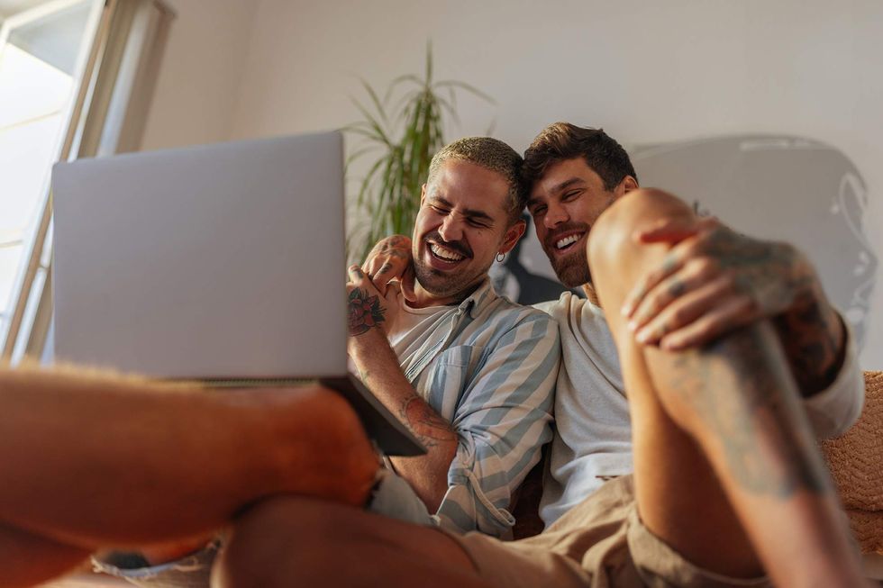 Two gay men looking at a laptop and laughing
