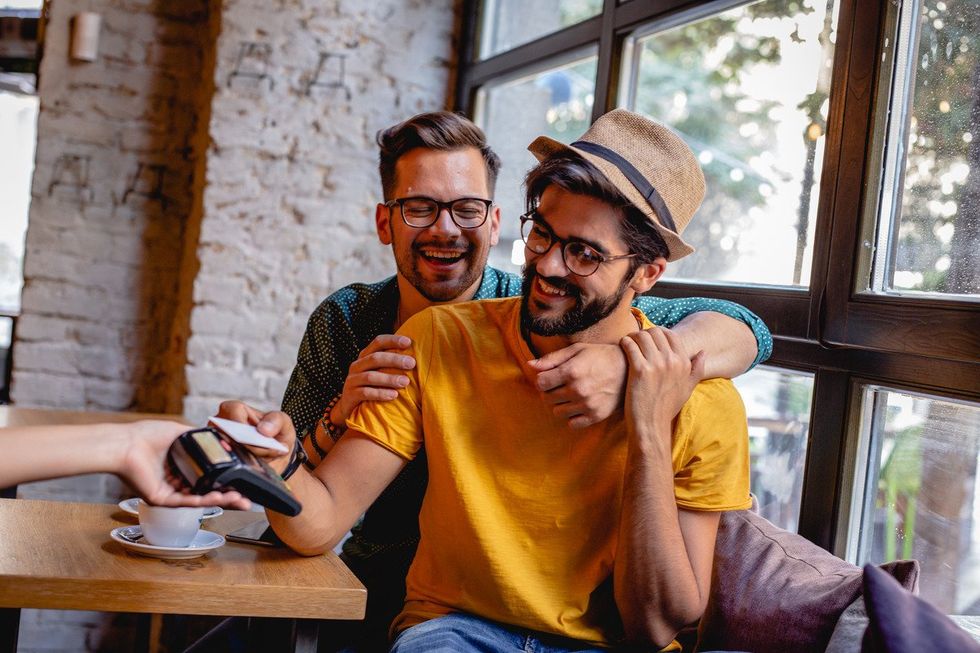 Two gay men pay in bar with credit card