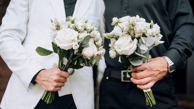 two grooms holding white flower bouquets for gay wedding