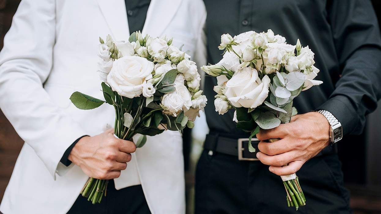 two grooms holding white flower bouquets for gay wedding