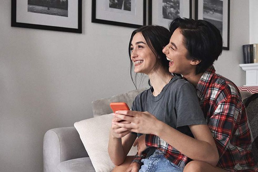 two lesbians looking at a cell phone and laughing