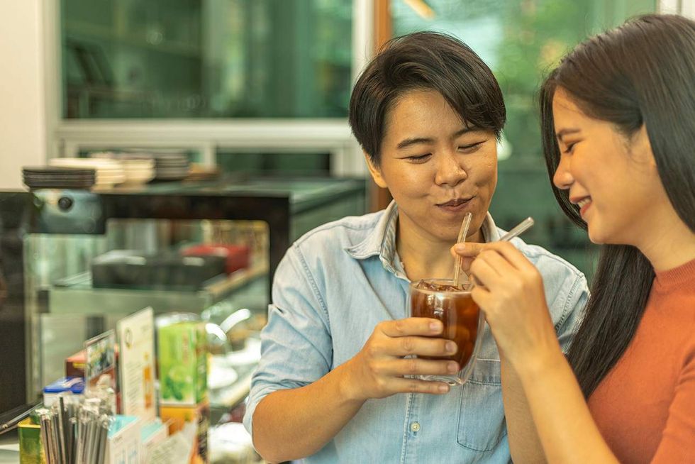two lesbians on a date, drinking out of the same cup of coffee