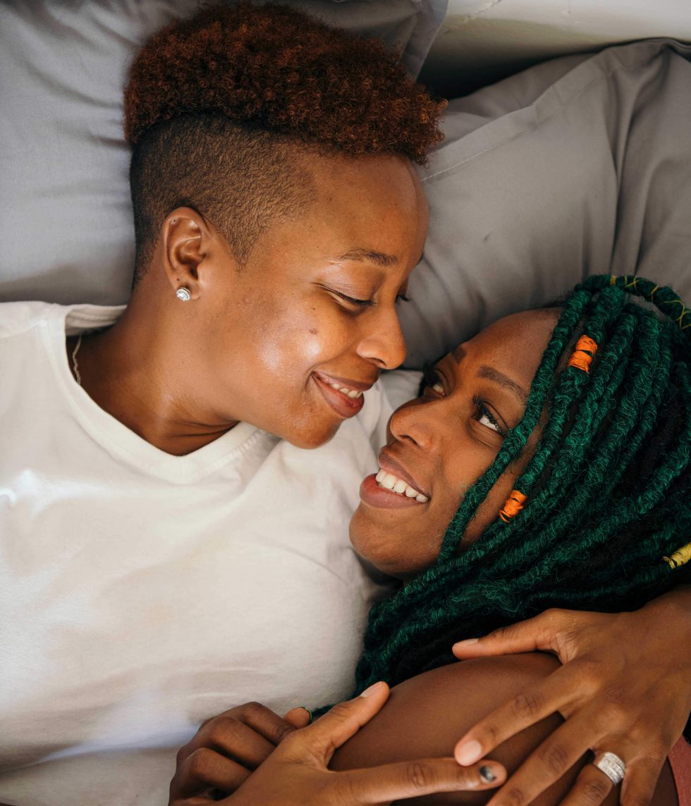 Two lesbinas holding each other in bed