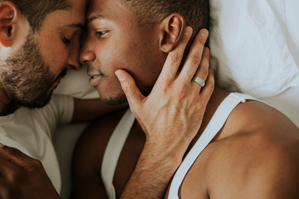 two men cuddling and kissing in bed