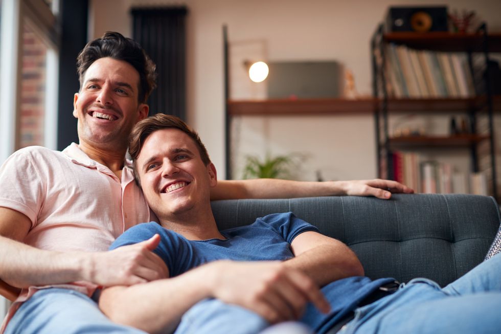 two men cuddling and watching TV