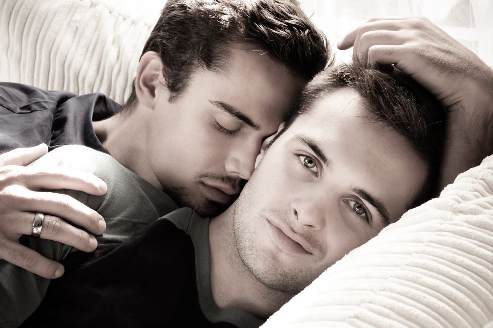 two men cuddling together in bed