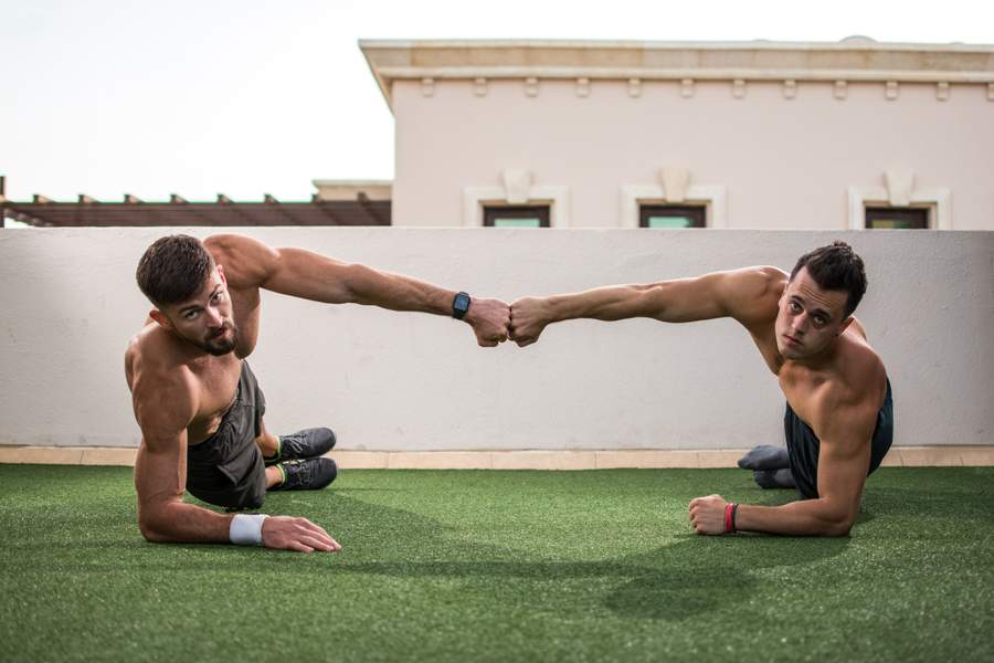 two men fist bumping in a forearm side plank
