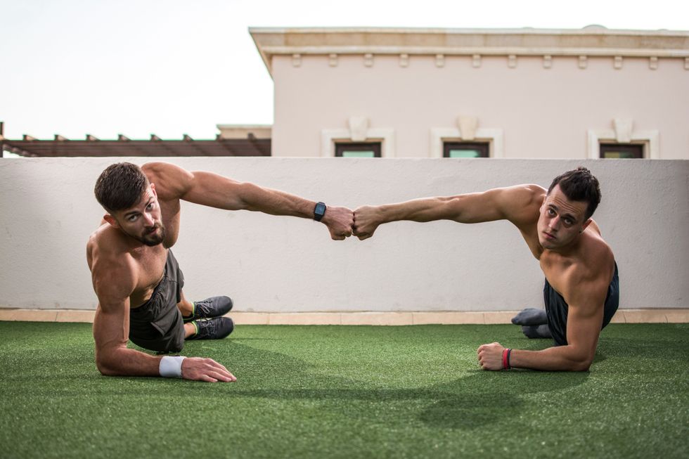 two men fist bumping in a forearm side plank