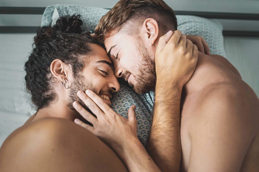 Two men holding each other in bed