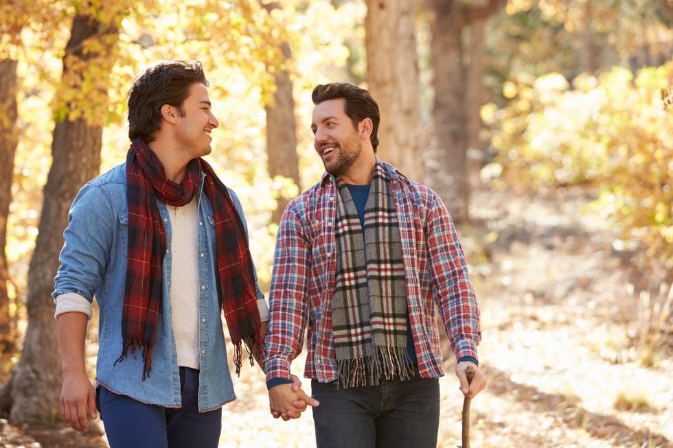 Two men holding hands on a walk through the fall leaves