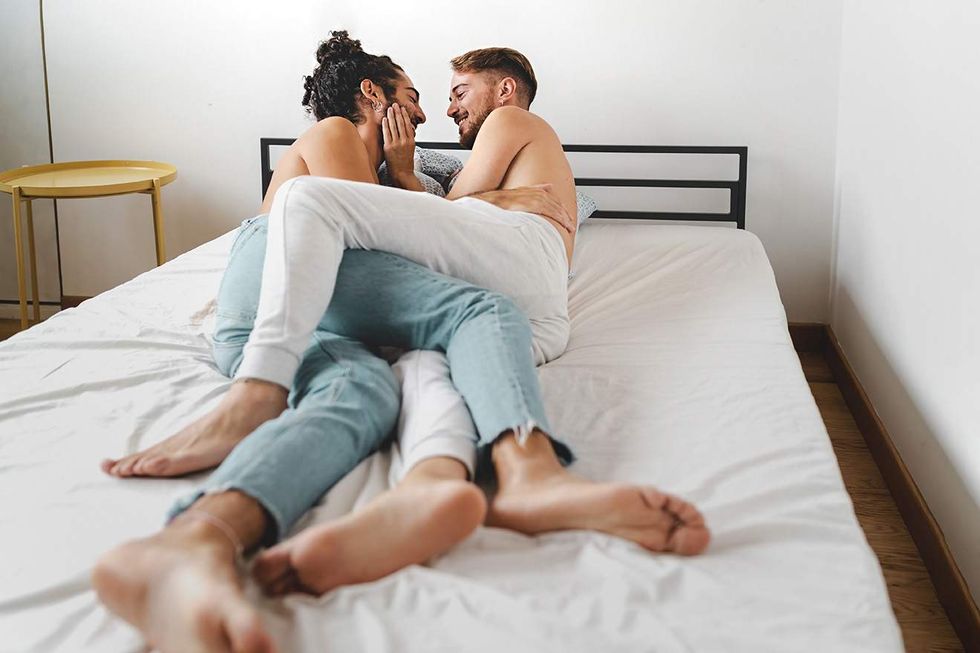 Two men in bed with their legs tangled together