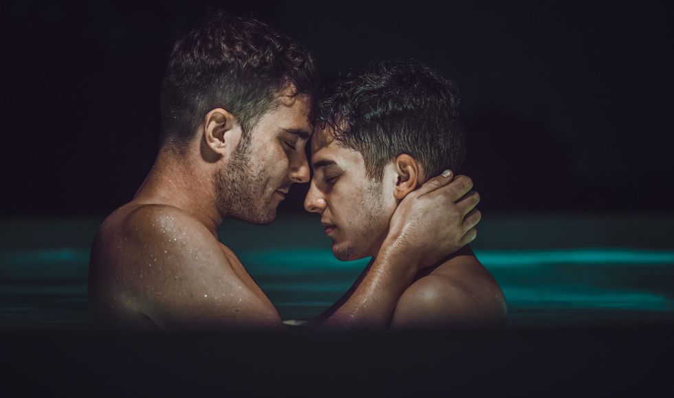 two men kissing in a pool