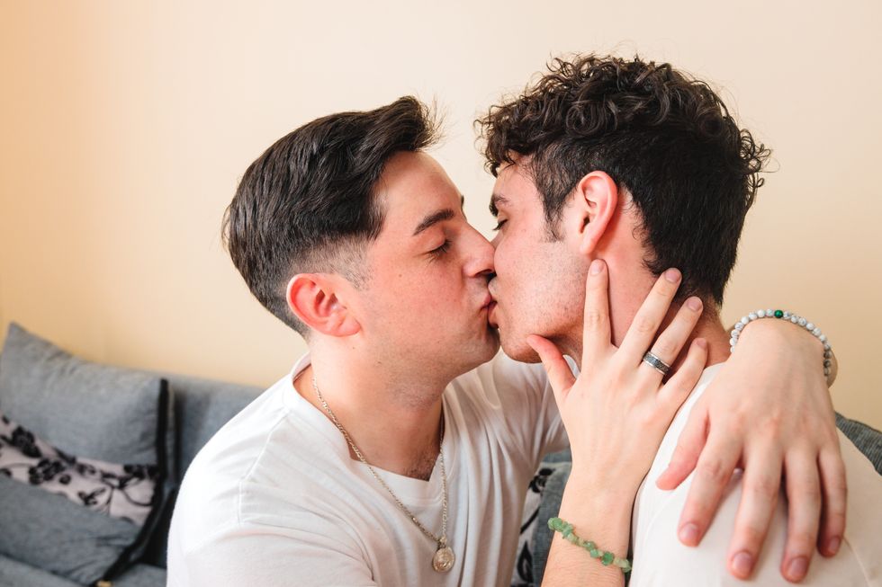 two men kissing in bed