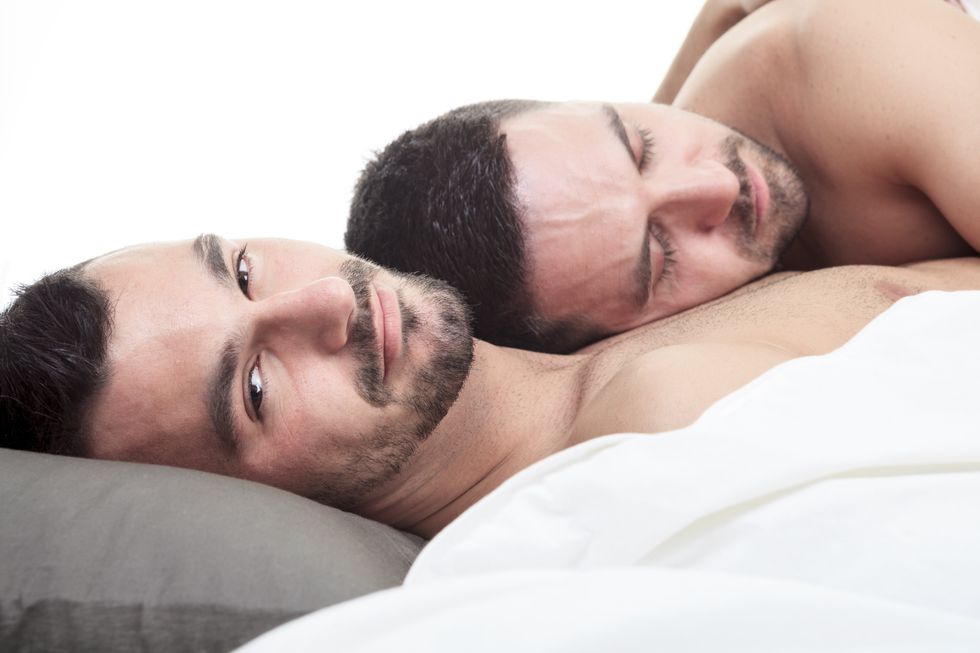 two men laying in bed together