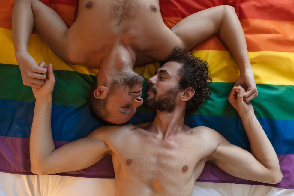 two men laying on a Pride flag