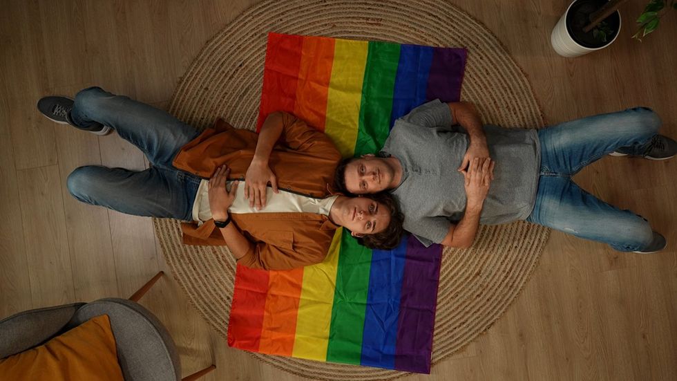 two men laying on a pride flag