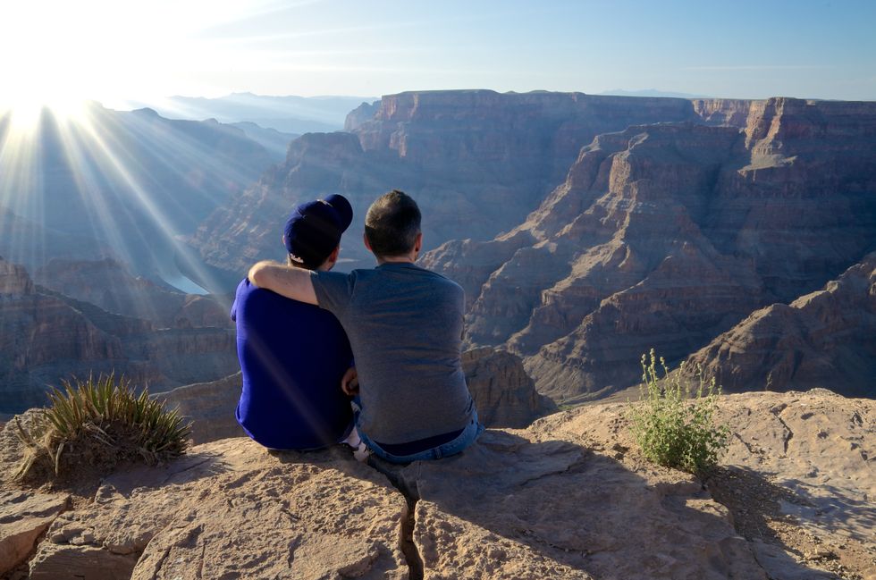 two men looking at the grand canyon and cuddling