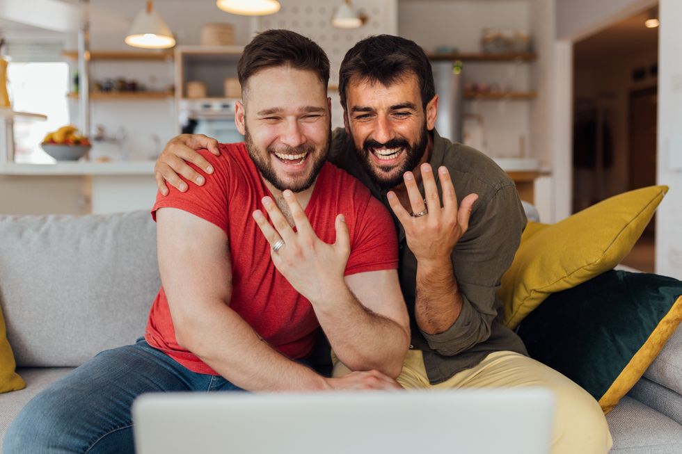 two men showing wedding rings and smiling
