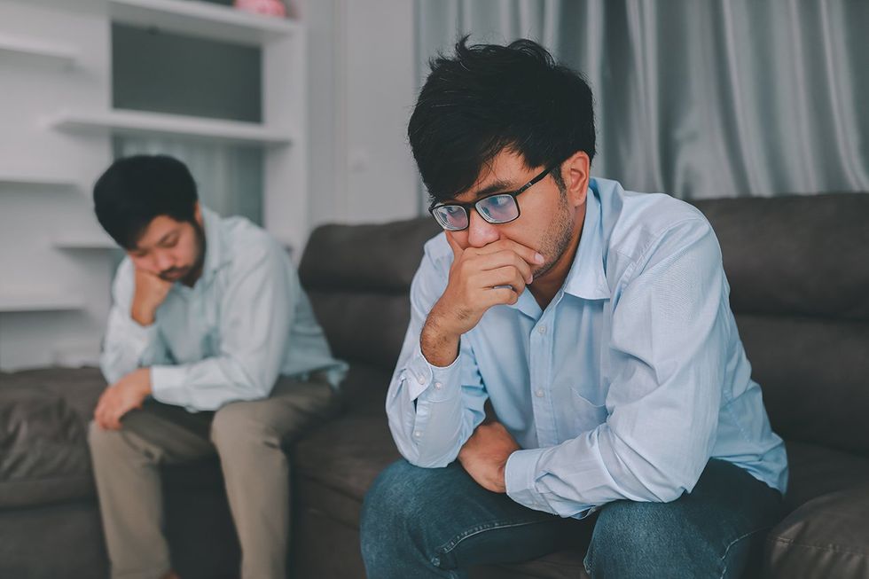 two men sitting opposite on a couch
