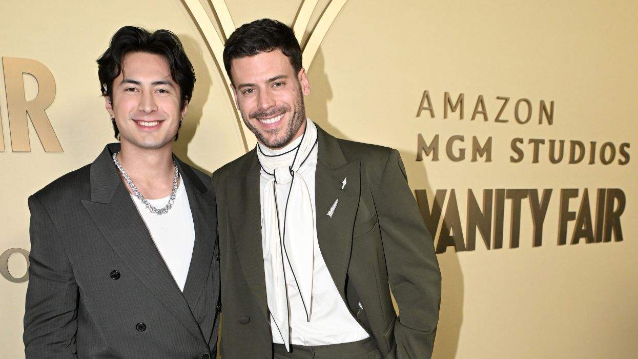 Two men smiling at Vanity Fair event backdrop.