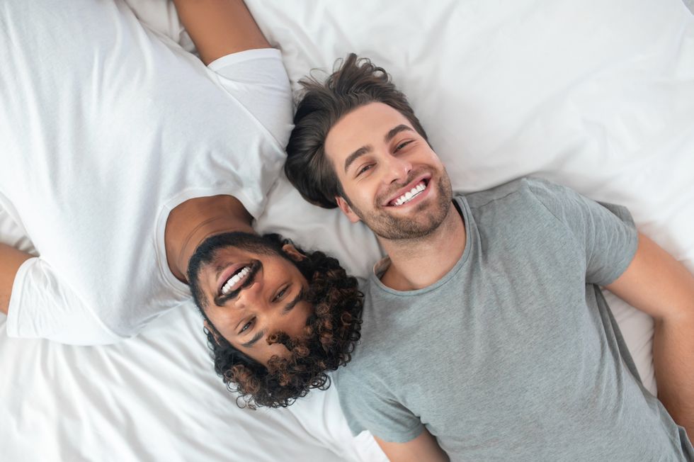 two men smiling in bed