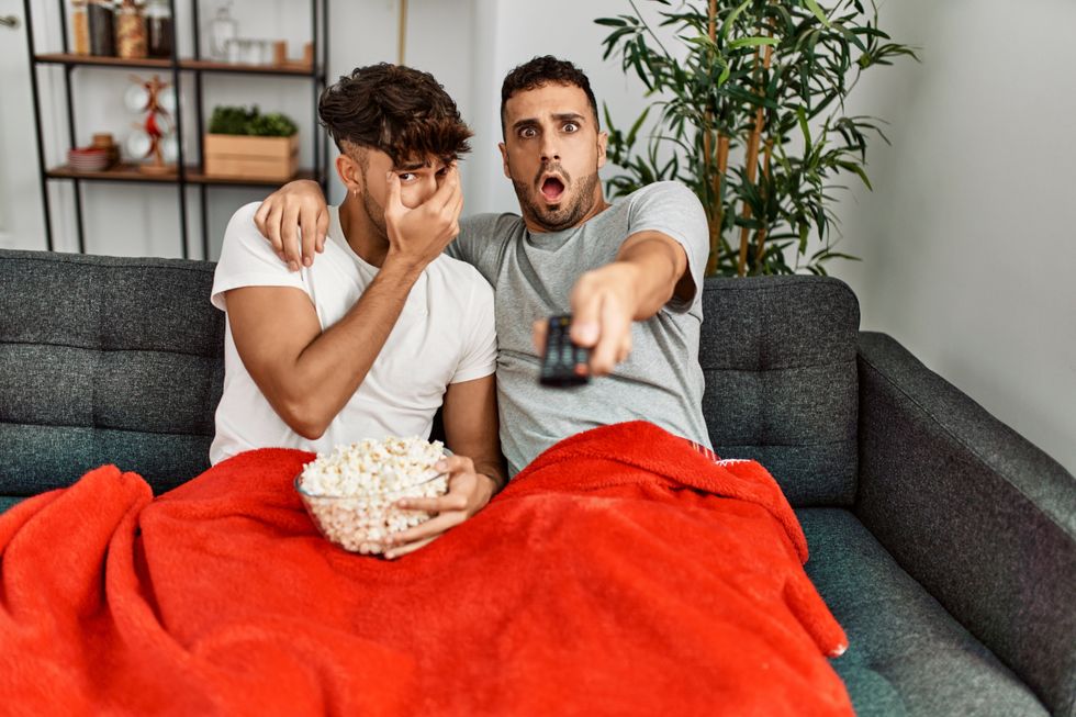 Two men watching a horror movie on the couch