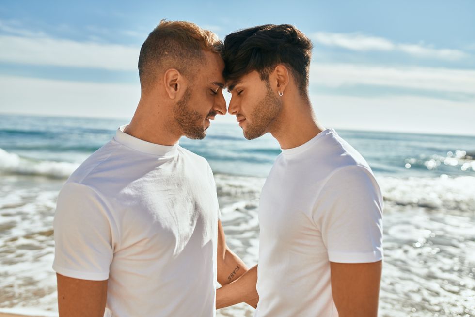 two men with their foreheads together on the beach