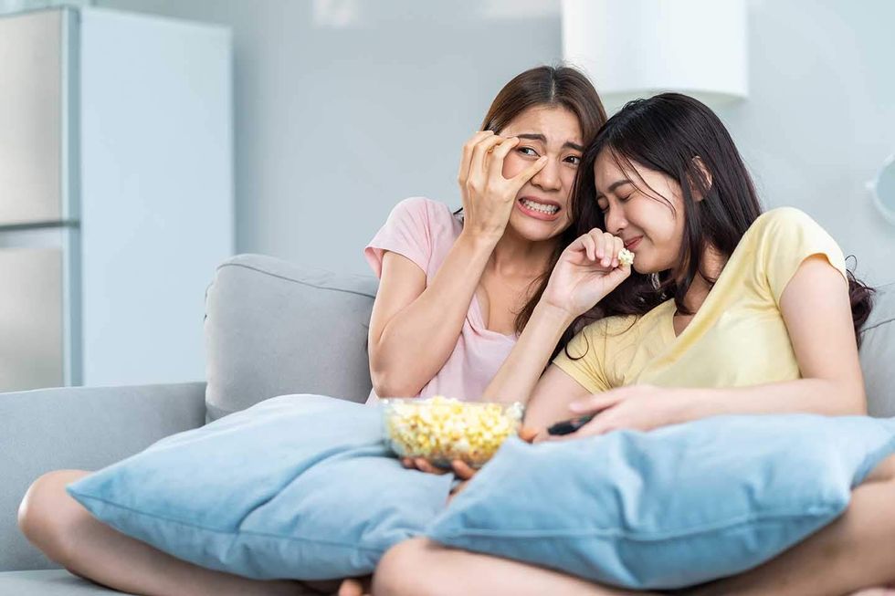 two woman eating popcorn and looking horrified