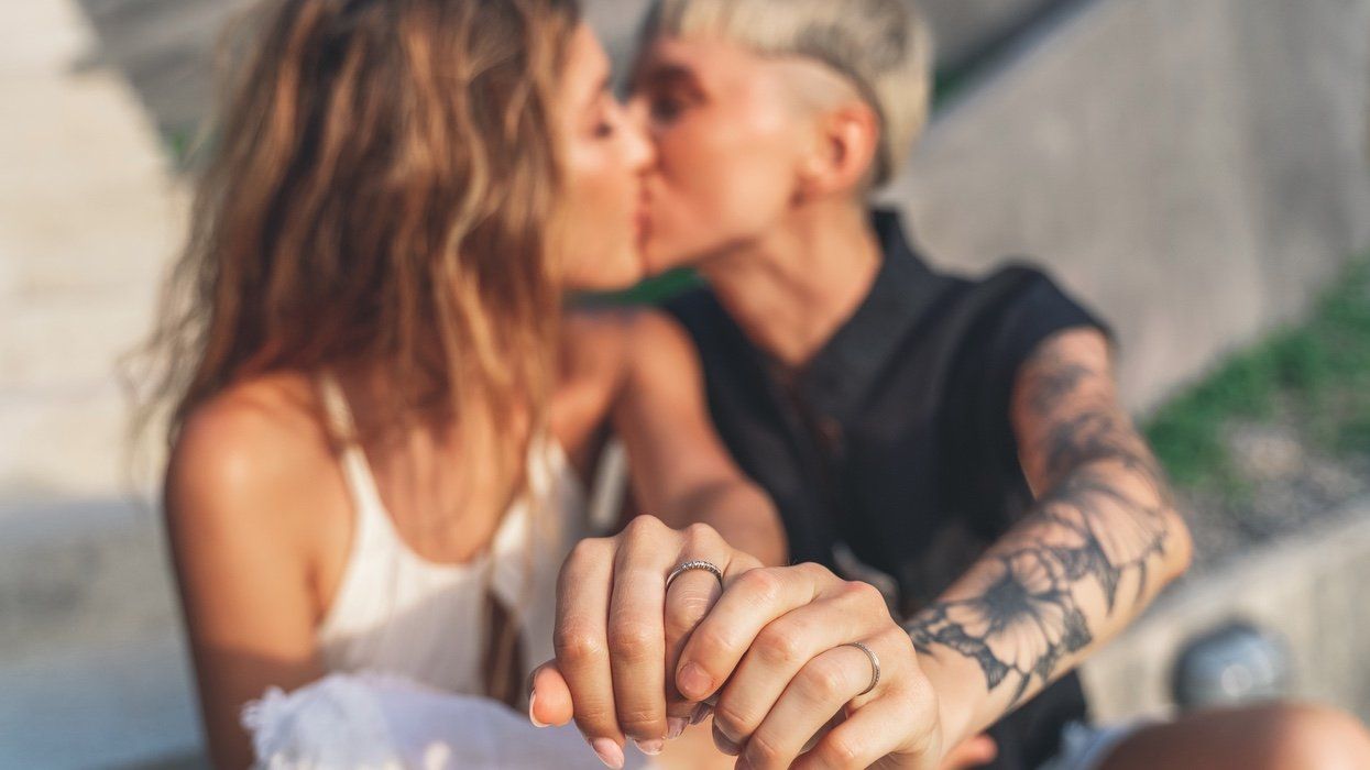 Two women kiss while showing off their rings