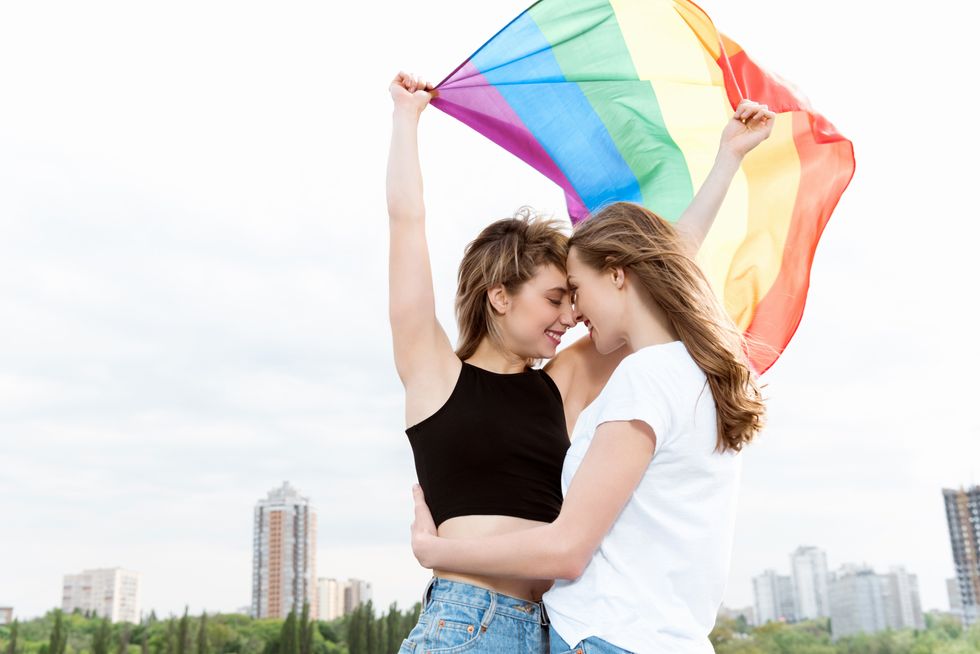 two women kissing under a pride flag