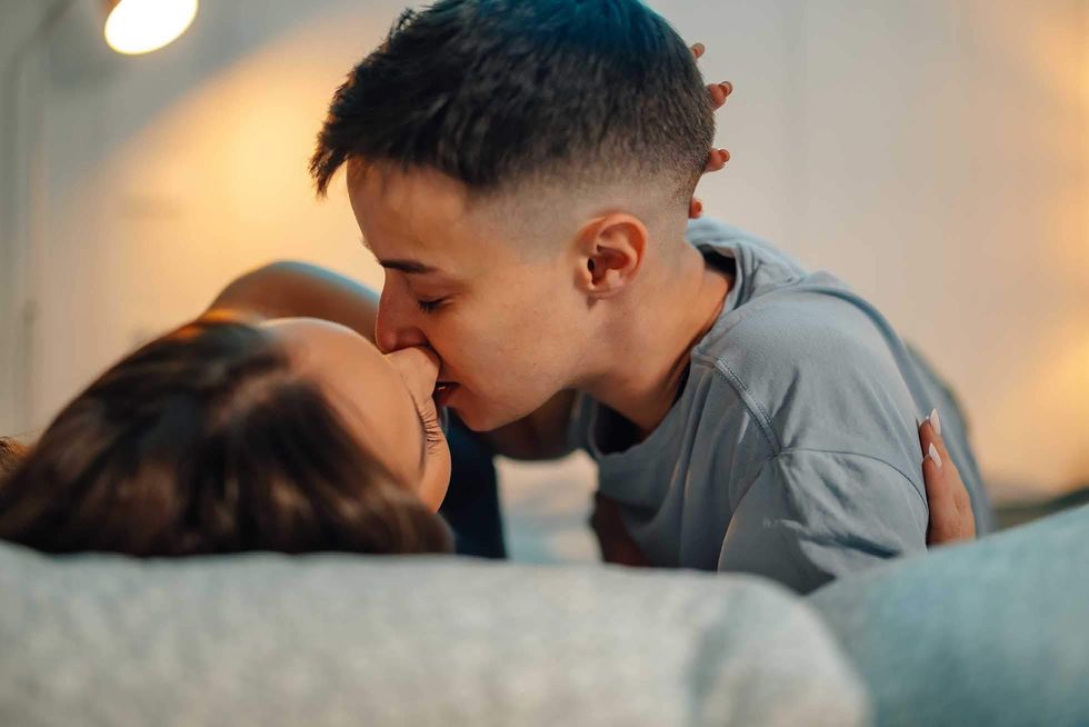 two women kissing while lying in bed
