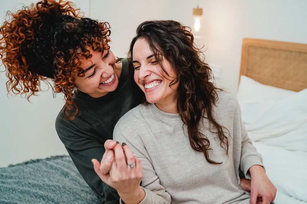 two women laughing and holding hands